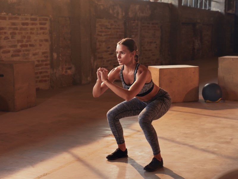 Frau, die im Fitnessstudio squattet