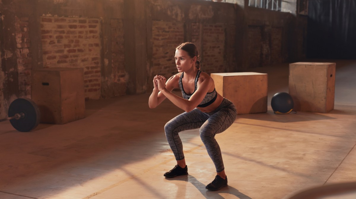 Frau, die im Fitnessstudio squattet