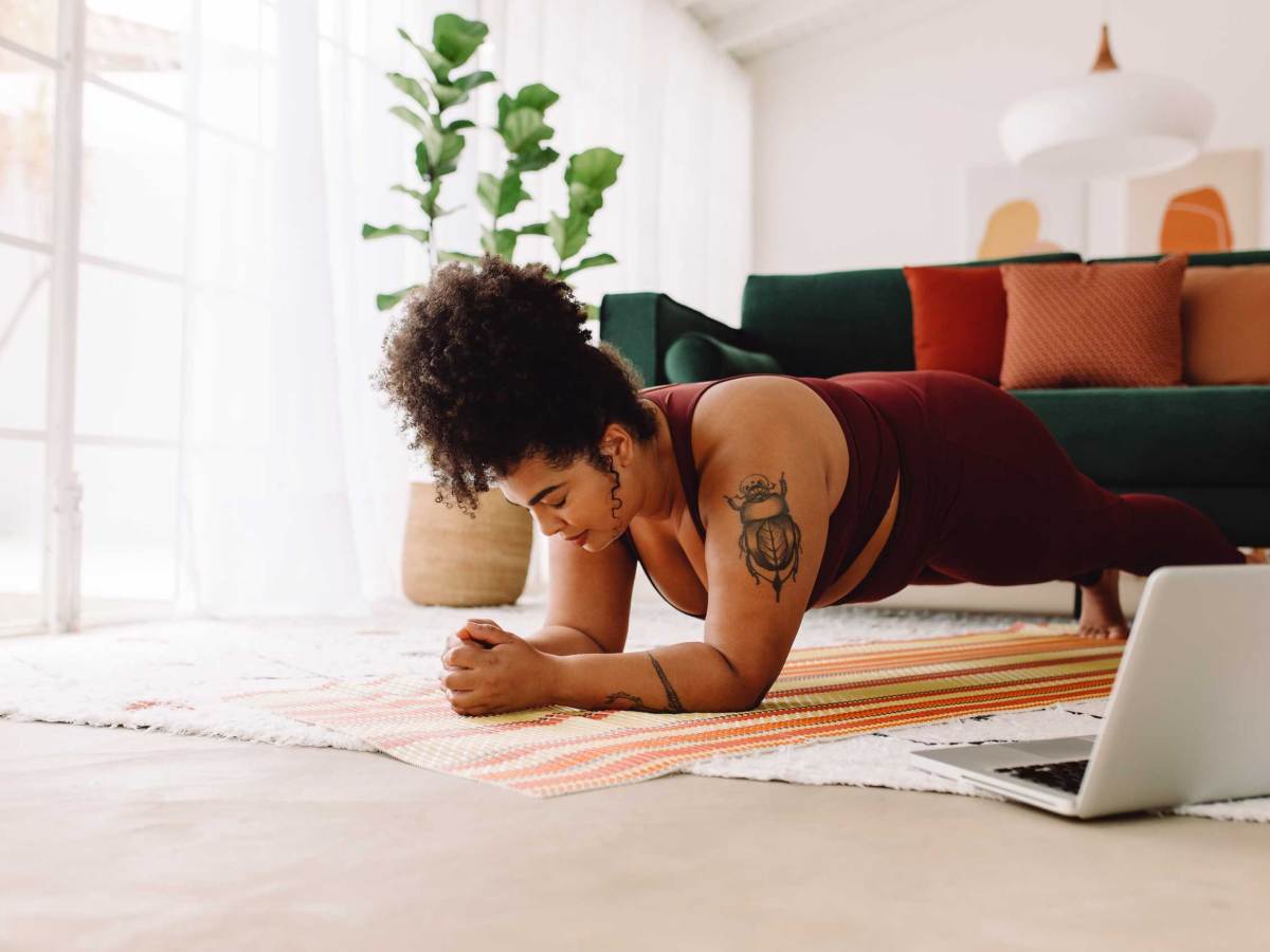 Frau macht Plank-Workout mit Laptop zu Hause