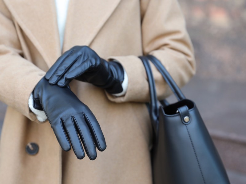 Frau zieht schwarze Lederhandschuhe an.