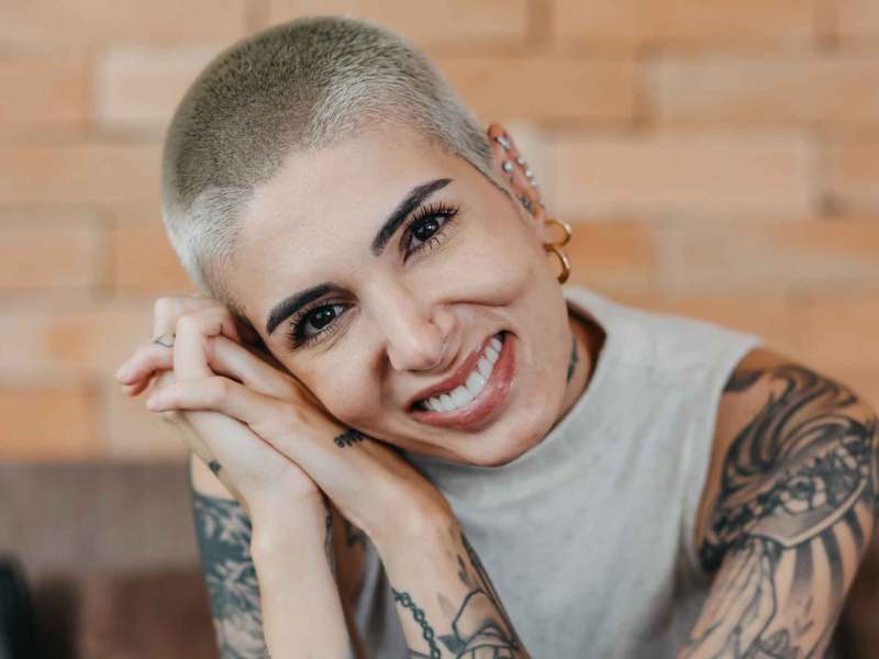 Frau mit Tattoos und blondem Buzzcut.