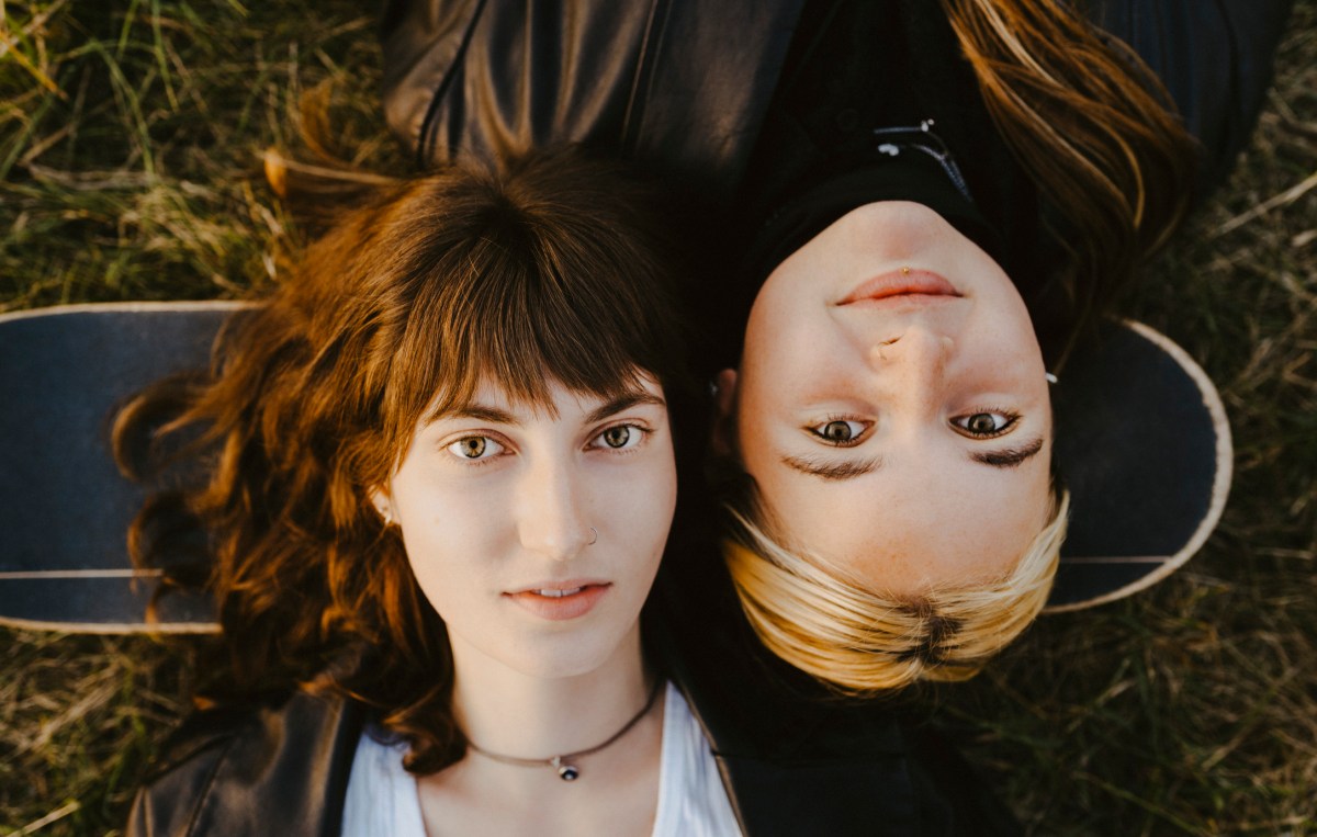 Zwei Freundinnen liegen auf dem Rücken im Gras