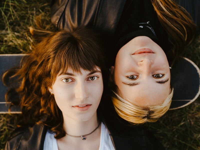 Zwei Freundinnen liegen auf dem Rücken im Gras
