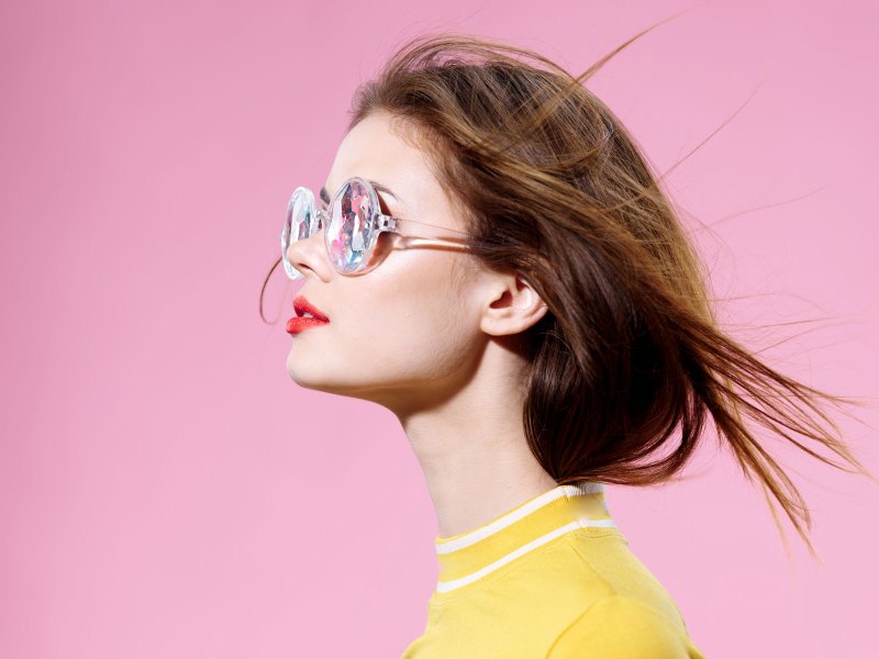 Frau mit Sonnenbrille vor einem pinken Hintergrund