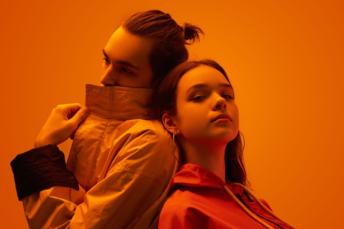 Junges Paar vor einer orangen Wand in orangem Licht