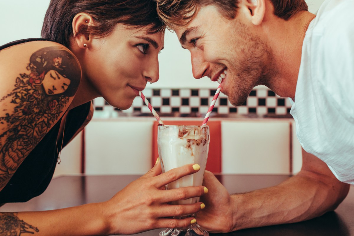 Eine Frau und ein Mann sind auf einem Date und teilen sich einen Milkshake.