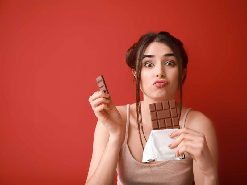 Frau vor rotem Hintergrund mit Tafel Schokolade