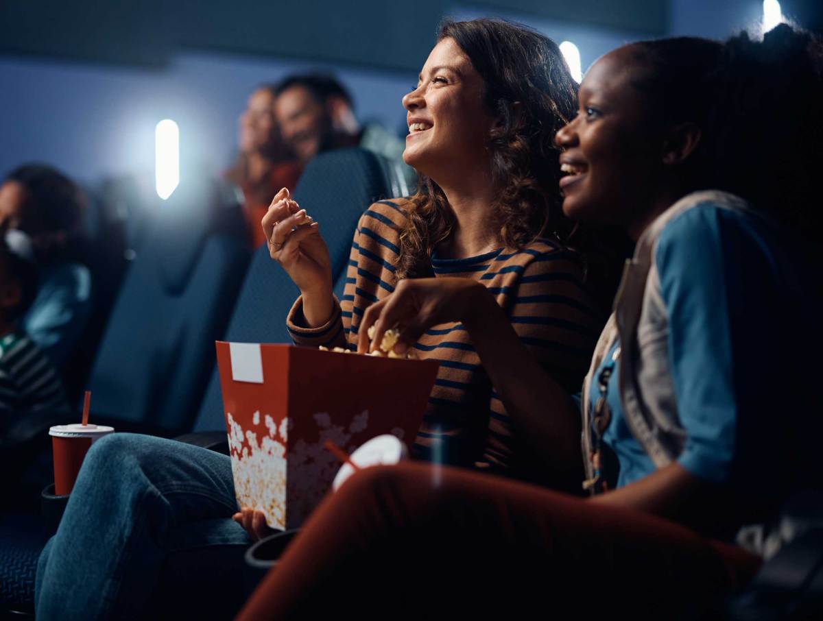 Junge Frau isst Popcorn, während sie einen spannenden Film im Kino sieht.