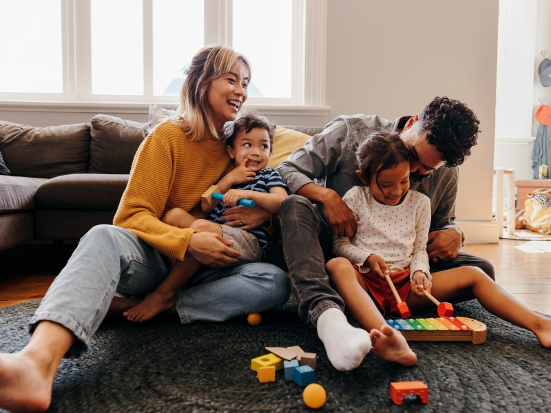 Mutter und Vater spielen mit Sohn und Tochter in ihrem Wohnzimmer.