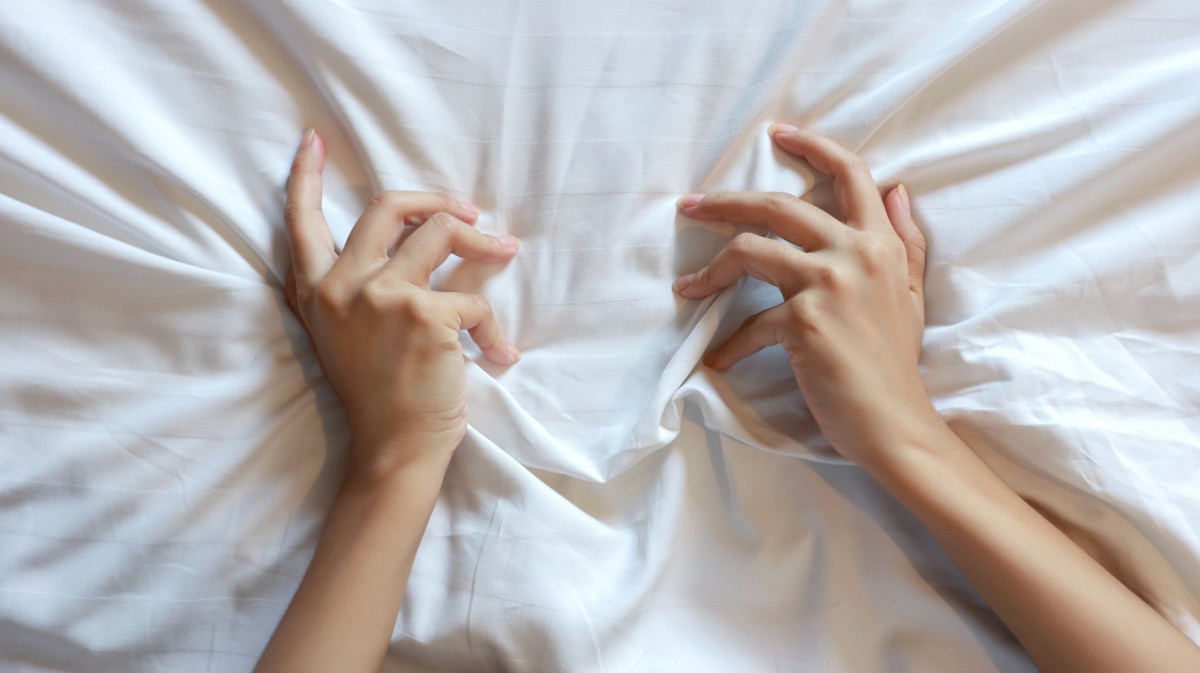 Zwei Hände einer Frau, die sich an einem Bettlaken festkrallen