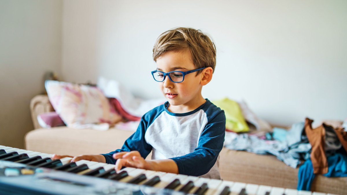 Junge, ca sechs Jahre, sitzt in seinem Zimmer am Keyboard.