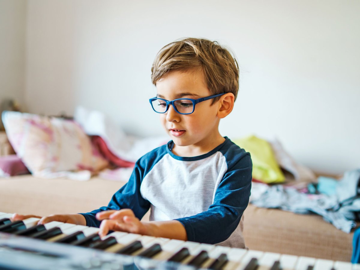 Junge, ca sechs Jahre, sitzt in seinem Zimmer am Keyboard.