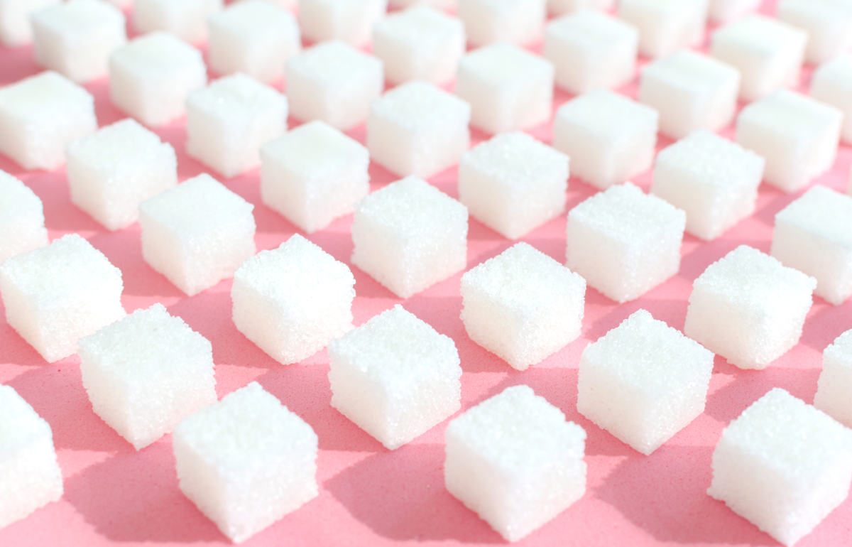 Raffinierter Zucker auf rosafarbenem Hintergrund, Würfel aus süßem und weißem Zucker in geometrischer Form.