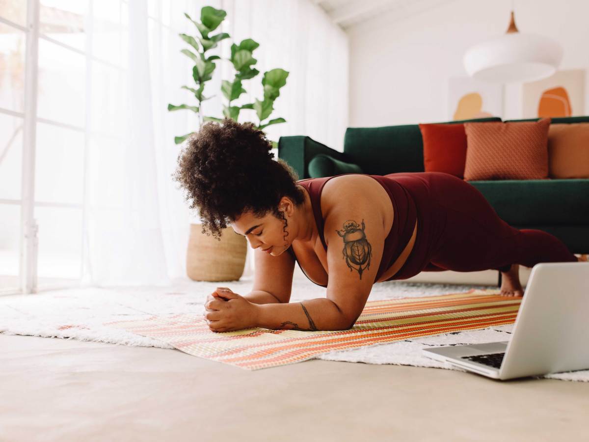 Frau macht Plank-Workout mit Laptop zu Hause
