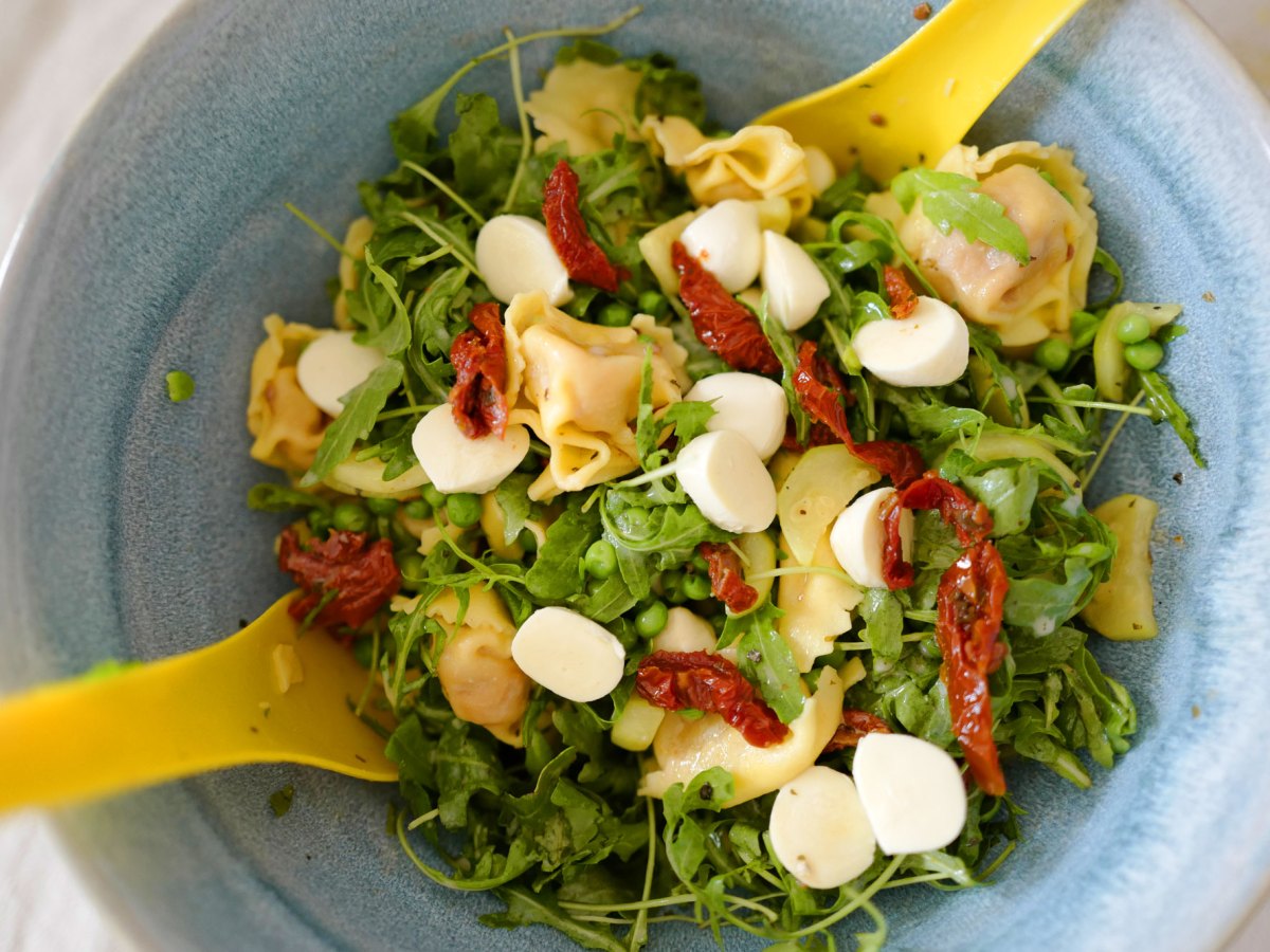 Schneller Salat zum Grillen: Tortellini Salat in blauer Schüssel mit gelbem Salatbesteck