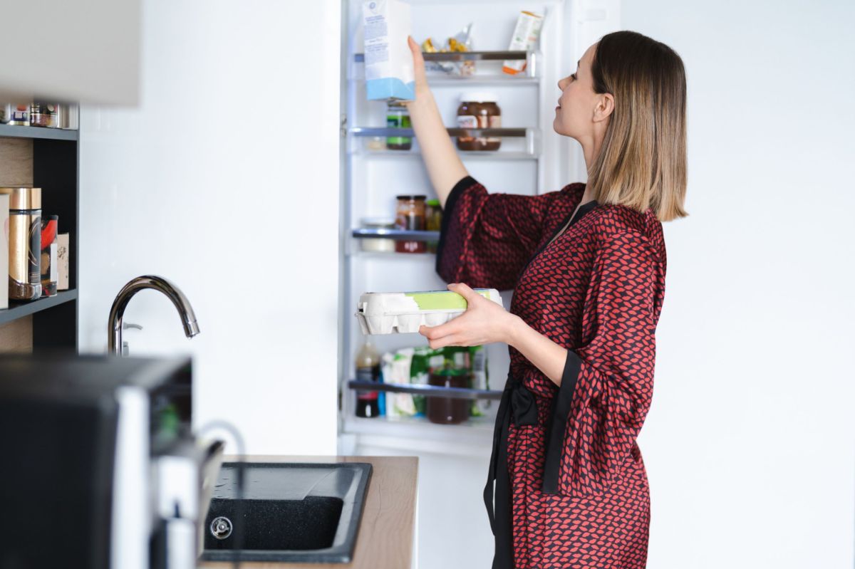 Eine Frau steht vor dem offenen Kühlschrank