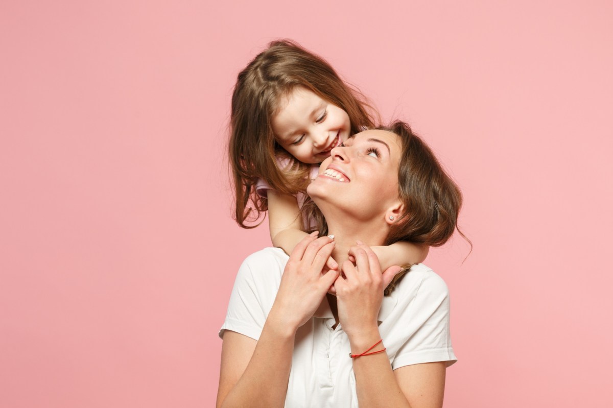 Mutter und Tochter vor einem rosafarbenen Hintergrund.