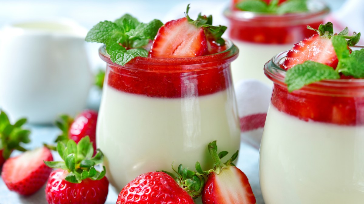 Gläser mit einer Dessert Creme und einem Erdbeerspiegel und frischen Erdbeeren oben drauf.