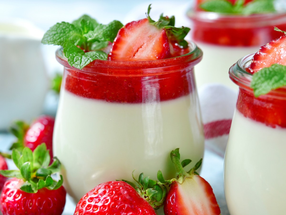 Gläser mit einer Dessert Creme und einem Erdbeerspiegel und frischen Erdbeeren oben drauf.