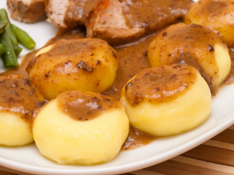 Schlesische Kartoffelklöße mit Bratensoße übergossen.