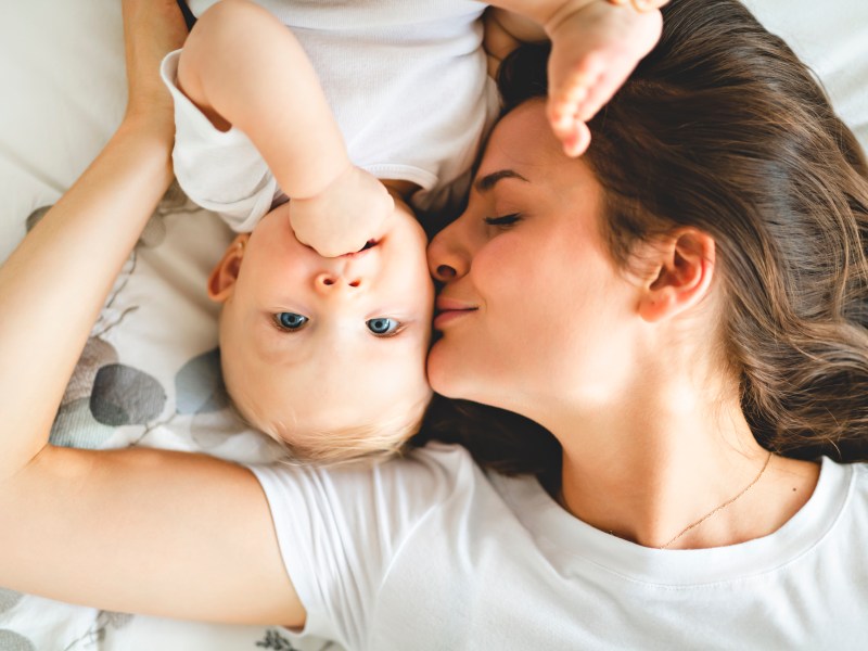 Mutter mit ihrem Baby auf dem Bett liegend.