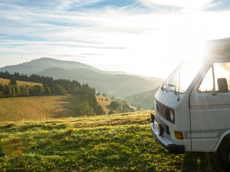 Vorderer Teil eines Campers auf einem Hügel inmitten der Natur beim Sonnenaufgang