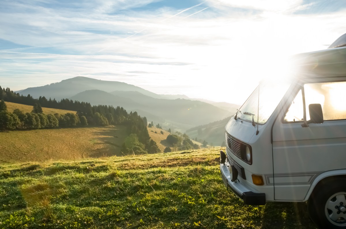 Vorderer Teil eines Campers auf einem Hügel inmitten der Natur beim Sonnenaufgang