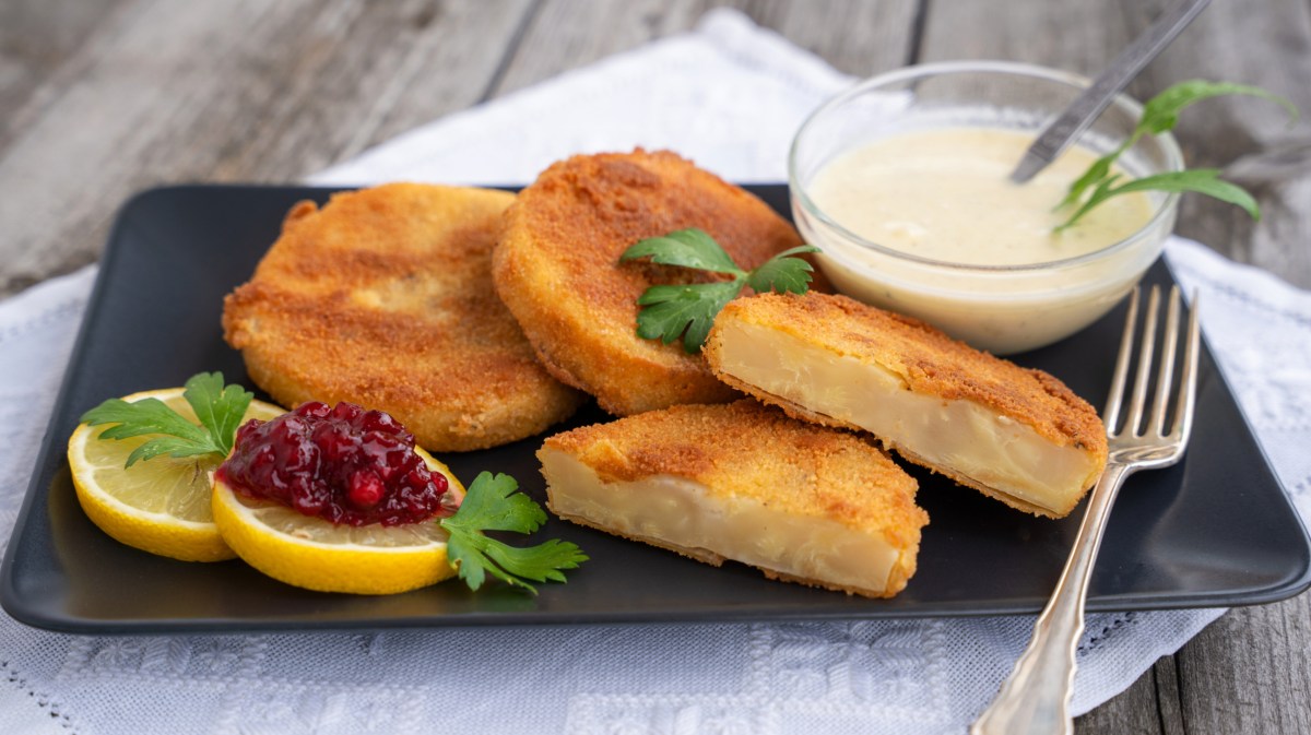 Vegetarische Sellerie-Schnitzel auf schwarzem Teller.