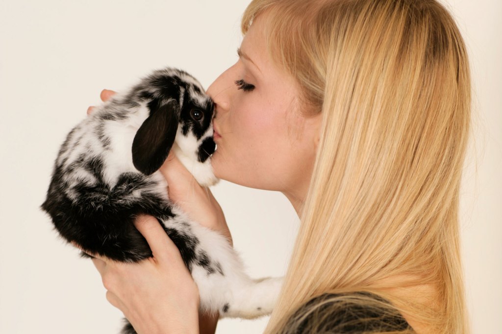 Frau küsst einen kleinen Hasen auf die Nase