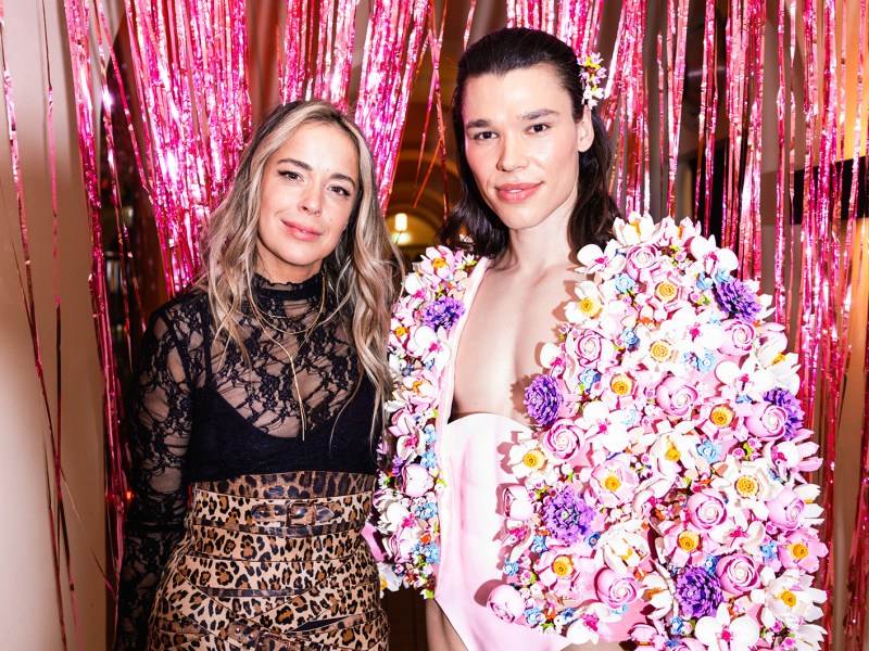 Marina Hoermanseder in schwarzer Spitzenbluse und Leo-Rock steht neben Helge Mark der ein mit Lego Botanicals besetztes Outfit trägt.