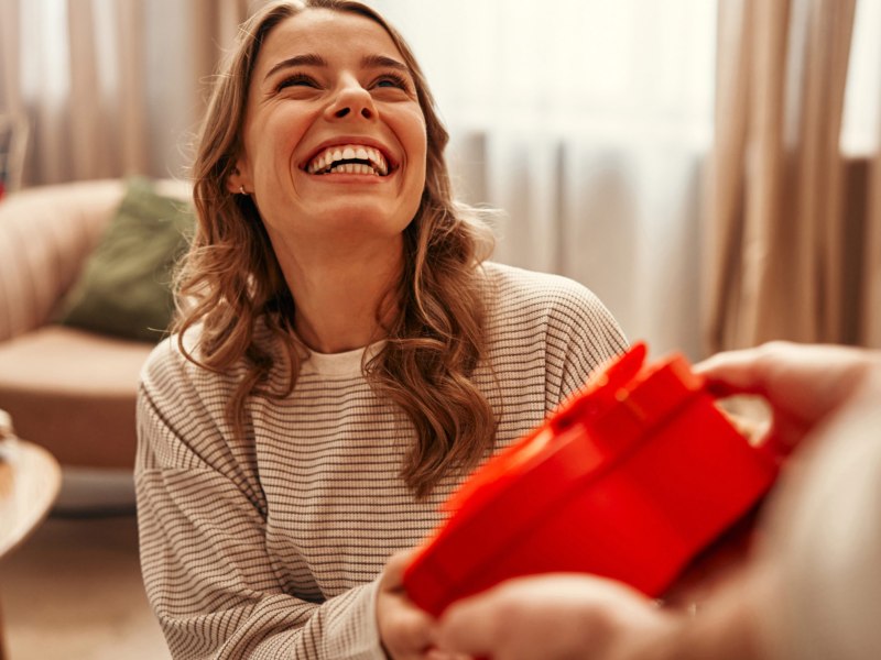 Junge Frau erhält ein Geschenk in Herzform zum Valentinstag.