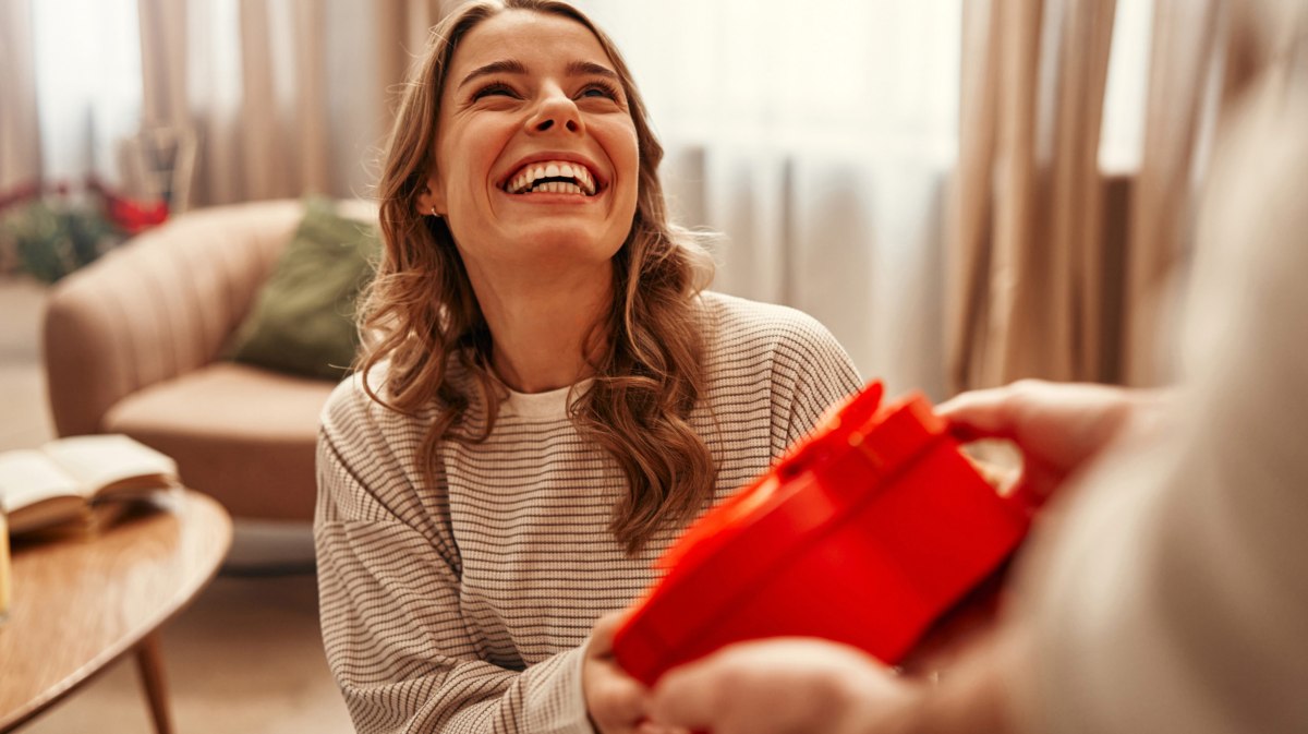 Junge Frau erhält ein Geschenk in Herzform zum Valentinstag.