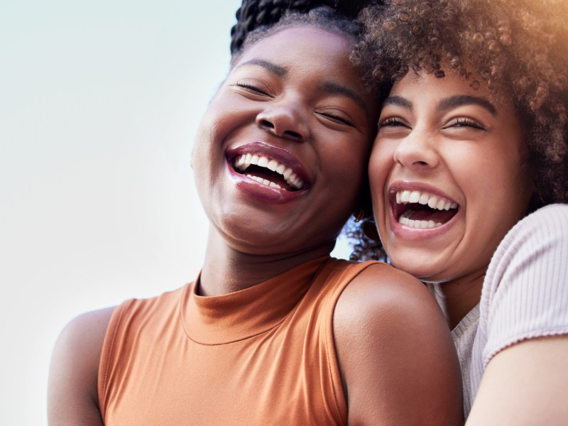 Zwei junge Frauen lachen und umarmen sich.