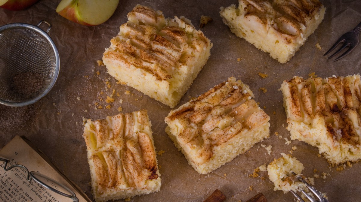 Apfelkuchen vom Blech auf braunem Tisch.