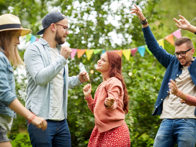 Freunde, die zusammen im Garten feiern und tanzen