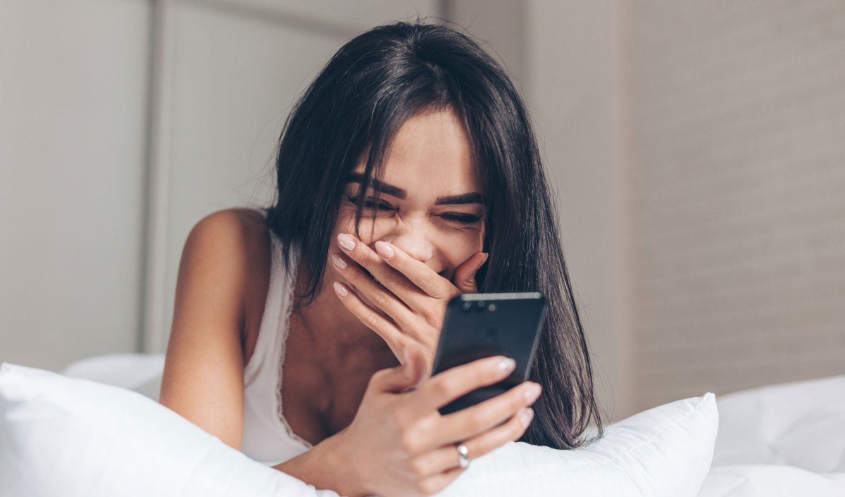 Frau schaut auf ihr Smartphone und lacht