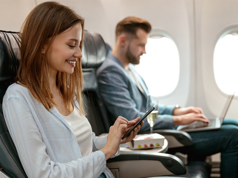 Frau, die mit ihrem Partner im Flugzeug sitzt und sich auf den Urlaub freut.