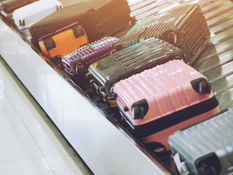 Bunte Koffer auf einem Gepäckband am Flughafen.