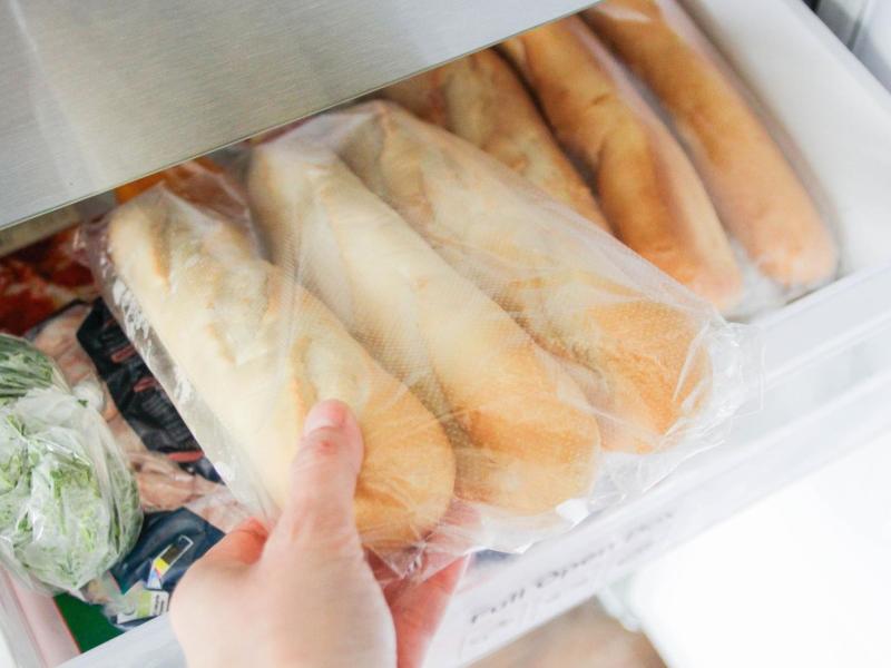 Person holt Baguettebrote aus dem Gefrierfach.