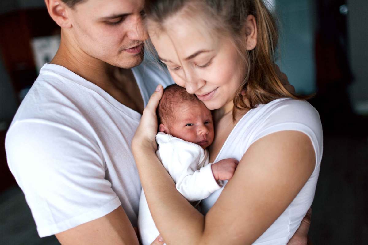 Junges Paar hält sein Neugeborenes in den Armen.