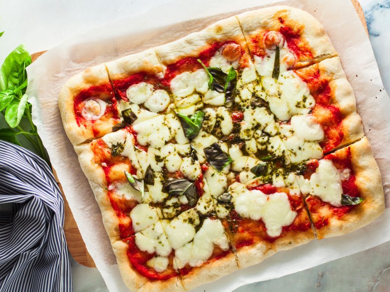 Quadratische selbstgemachte Pizza Margarita von oben fotografiert.