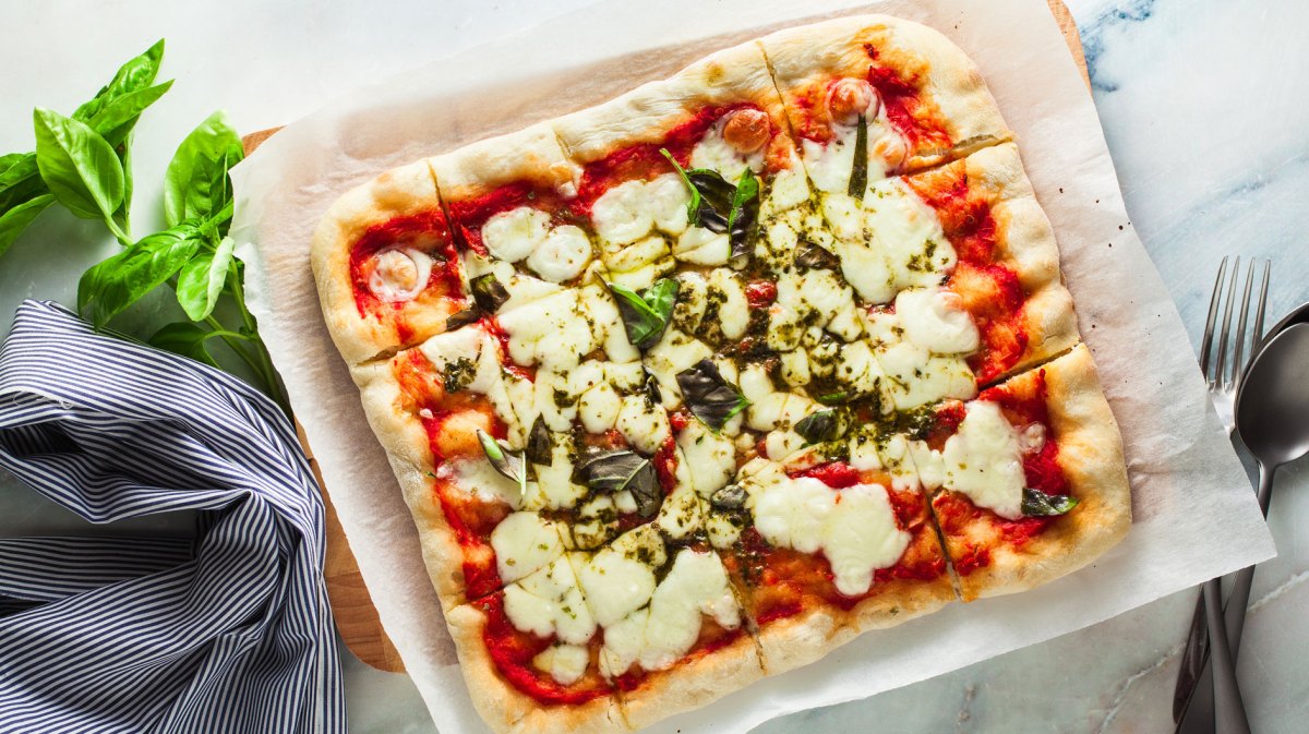 Quadratische selbstgemachte Pizza Margarita von oben fotografiert.