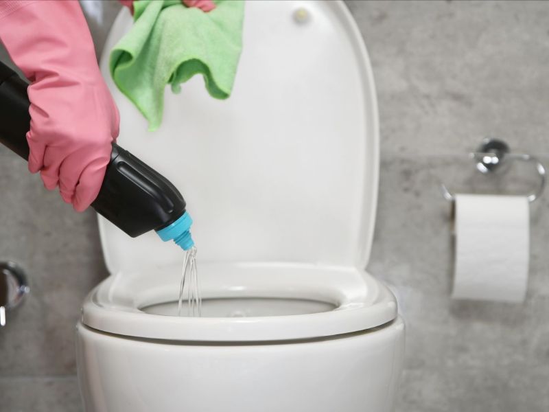 In eine Toilette wird Reiniger hineingetan, um Kalk zu entfernen