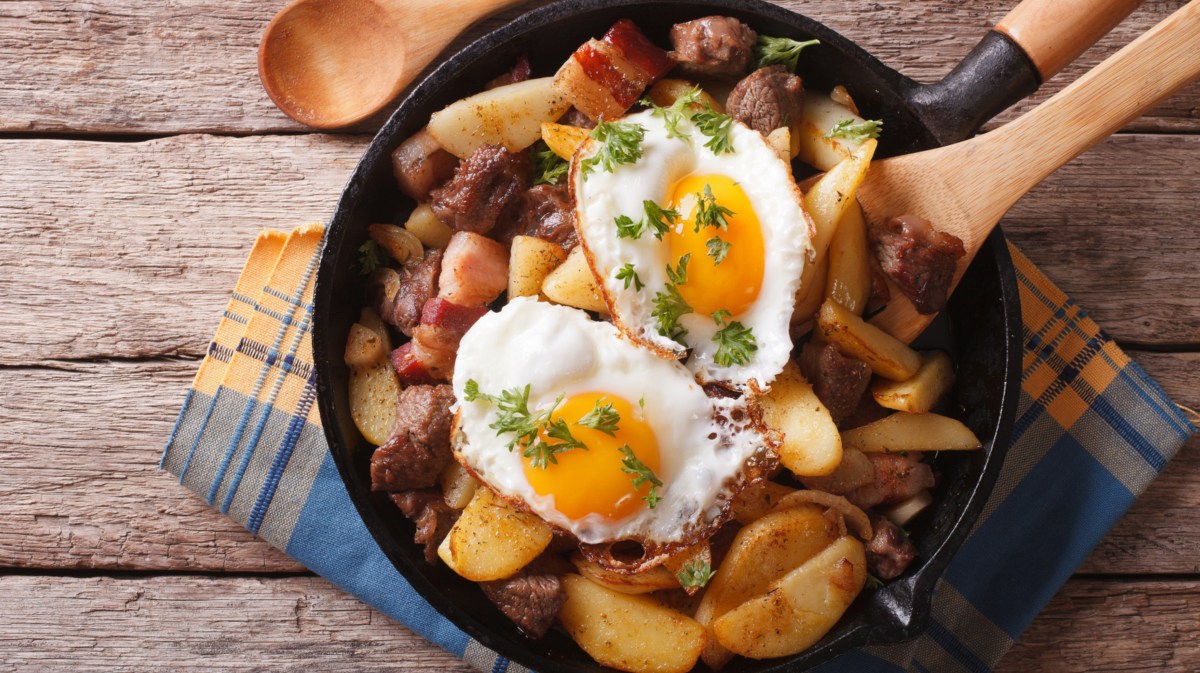 Angebratene Kartoffeln in Pfanne mit zwei Spiegeleiern.