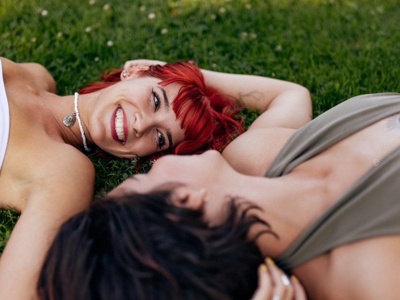 Zwei Frauen auf einem Rasen, die sich verliebt anschauen und anlächeln