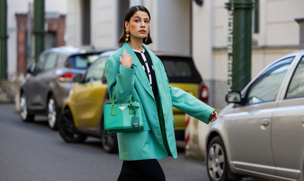 Streetstyle: Frau mit kurzem braunen Haar trägt schwarzes Kleid und knallig grüne Jacke