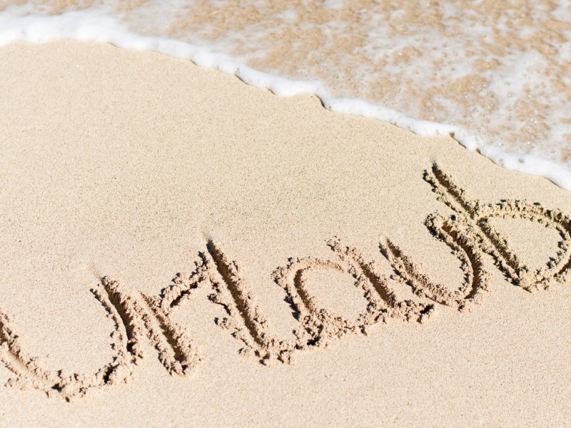 Der Begriff Urlaub wurde in den Sand geschrieben.