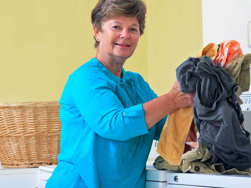 Wäsche stinkt nach dem Waschen: Ältere Frau sortiert Wäsche in Maschine