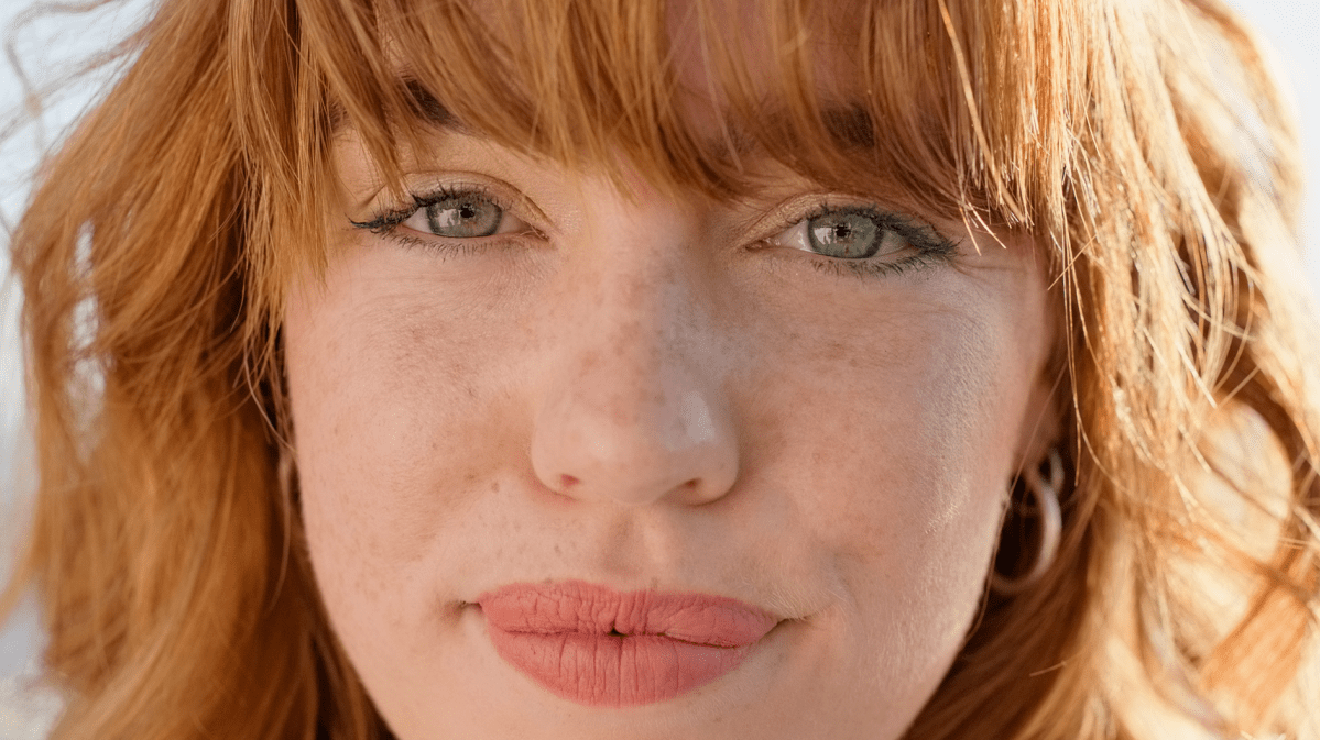 Frau mit roten Haaren, heller Haut und Sommersprossen