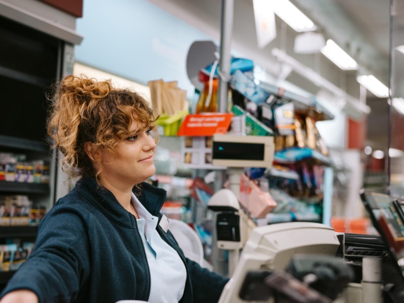 Frau an einer Supermarktkasse, die nett zur Seite lächelt